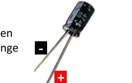 Primer plano de un condensador con pata larga (+) y pata corta (-)